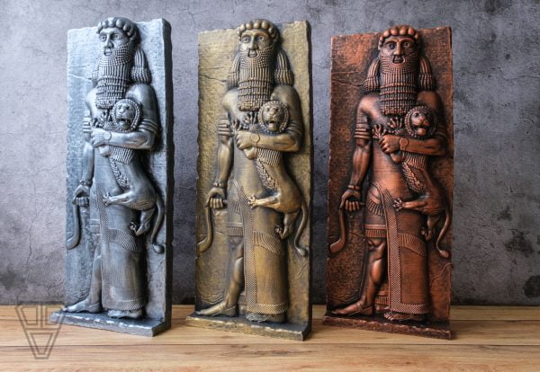 Gilgamesh Sculptures standing on a wooden table in front of an old plastered wall. Silver, gold and copper colors.